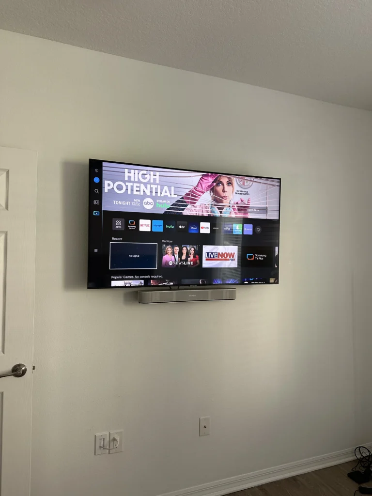 TV with a soundbar attached under it on a drywall wall. No cables showing.