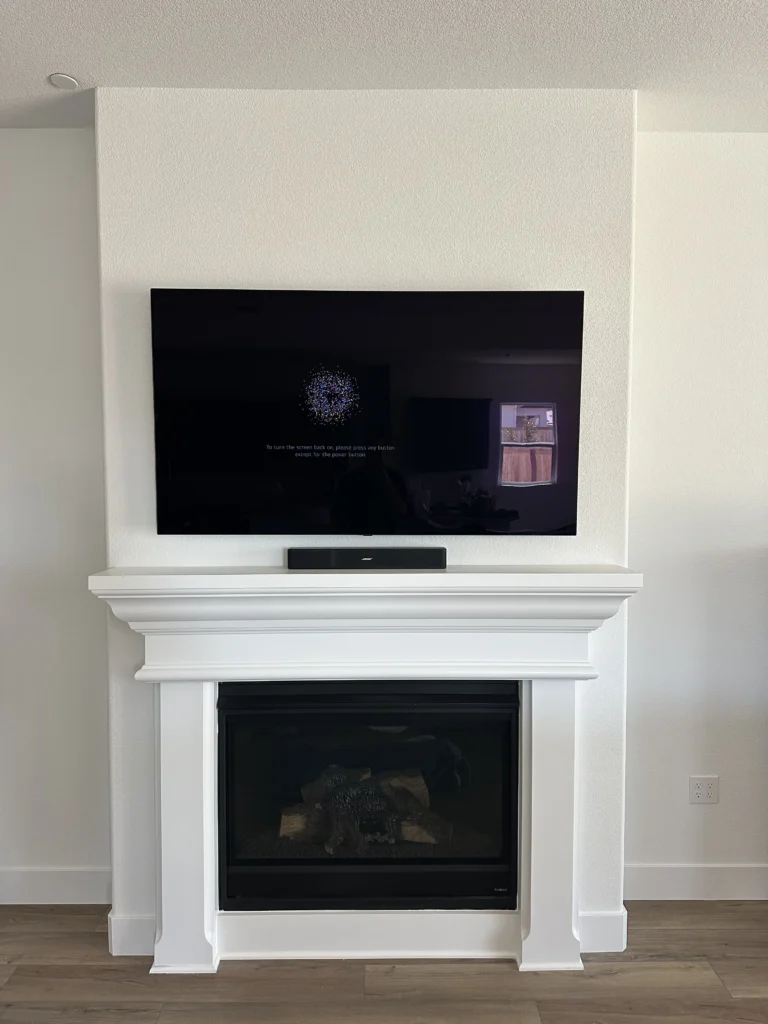 TV above the mantel, with a compact soundbar set on the mantel shelf.
