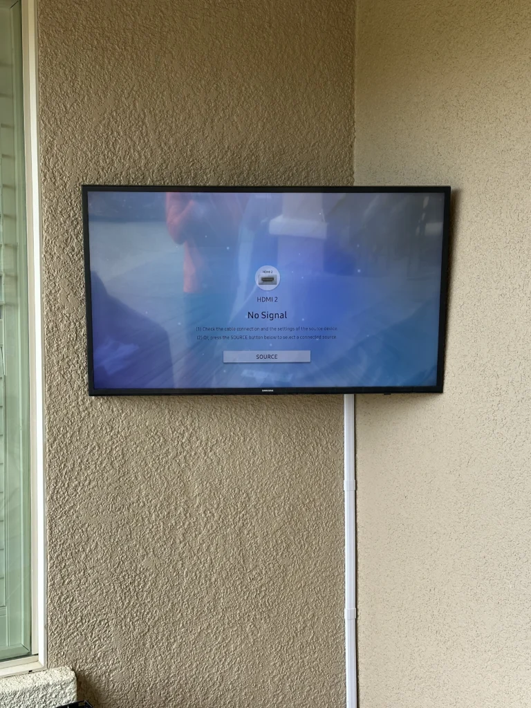 TV on a textured stucco wall, with the cable run down in a cord cover.