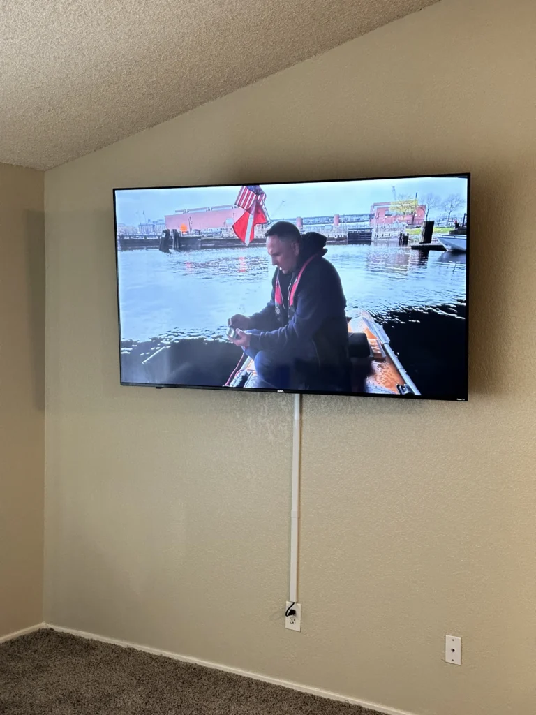 TV under a sloped ceiling, cable in a white cord cover down to the outlet.