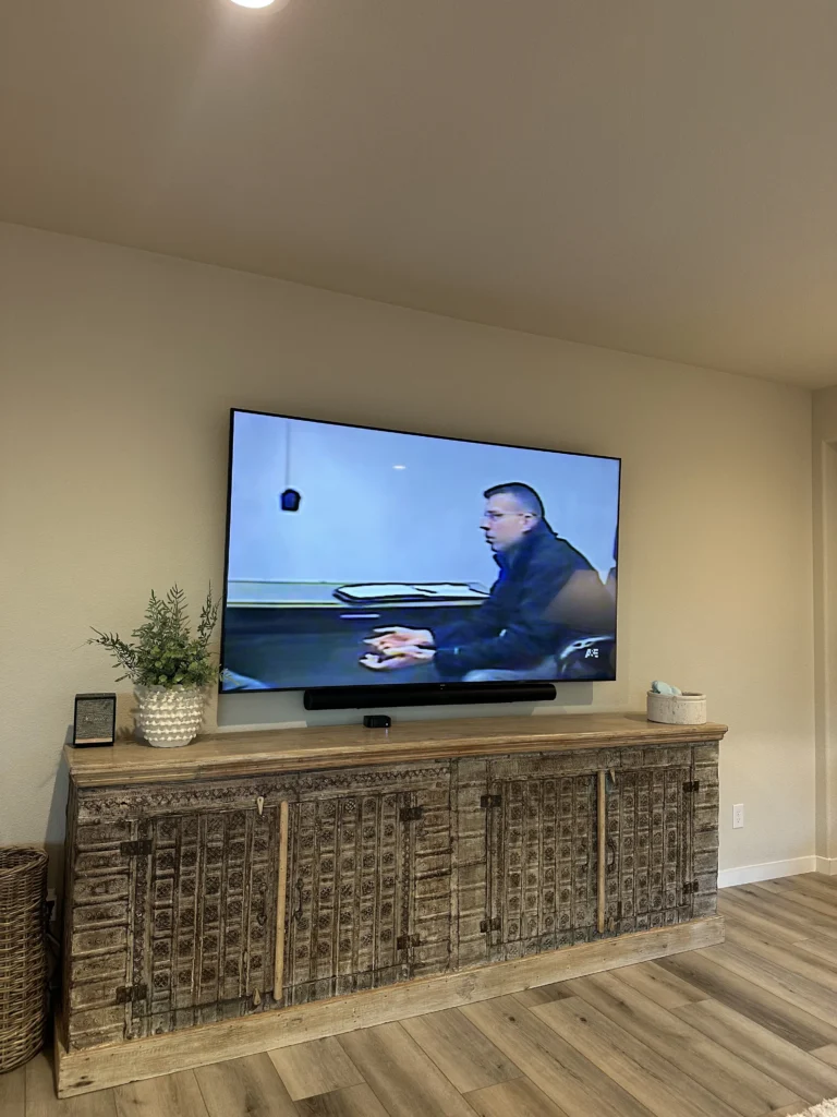 Large TV on drywall with a soundbar mounted under it, above the customer’s console.