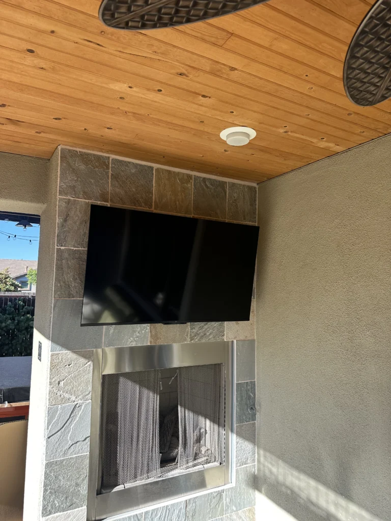 Covered patio: TV on a tilting mount over a slate-tile fireplace.