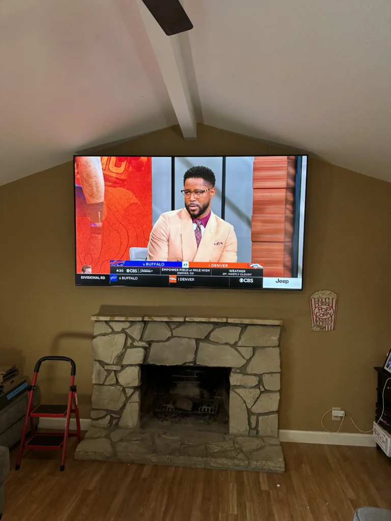 TV above a stone fireplace under a vaulted ceiling.