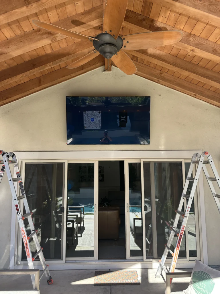 Covered patio: TV mounted high on the gable wall under a vaulted wood ceiling.