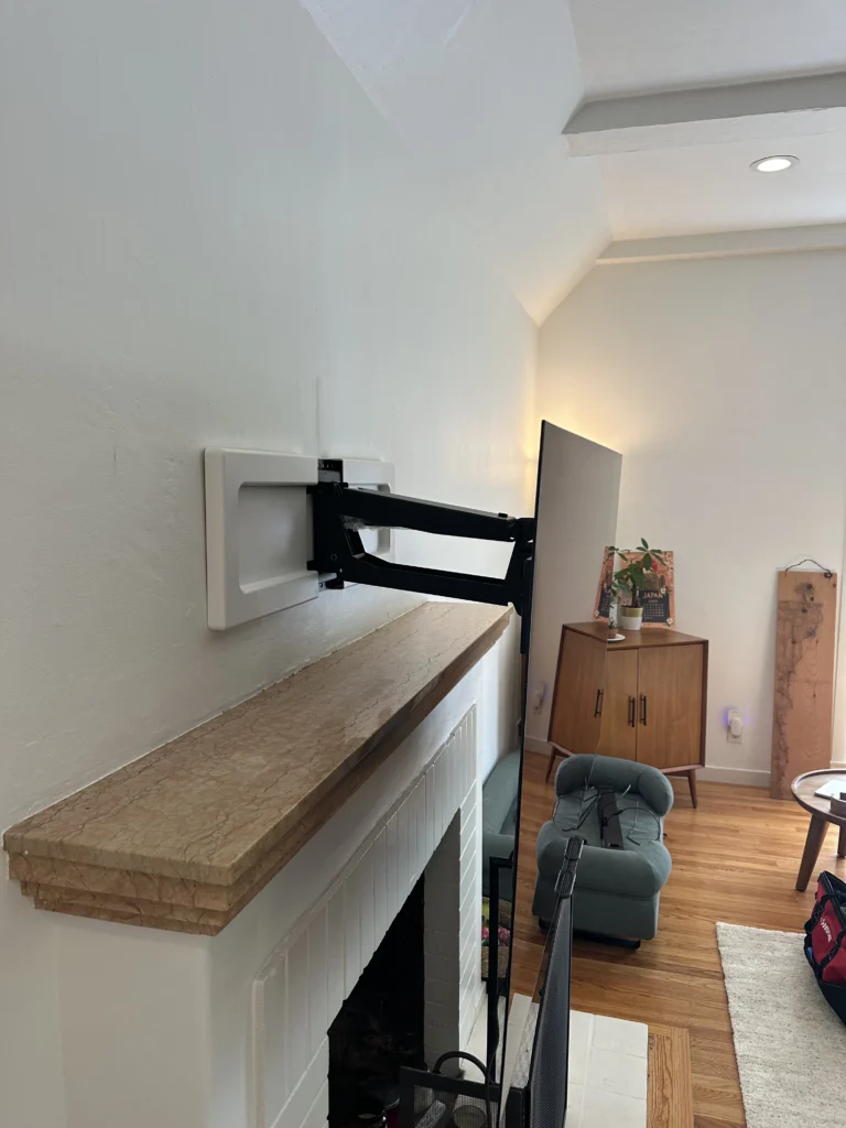 Pull-down mount installed above the mantel, so the TV lowers to eye level.